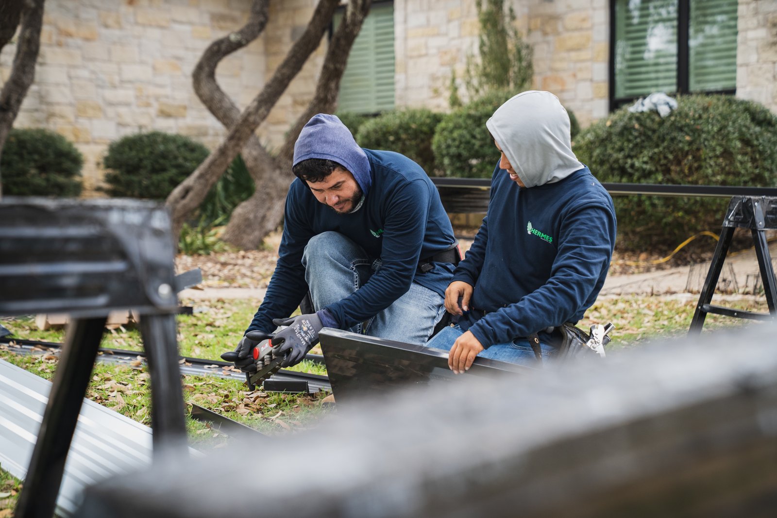 Two crew members preparing metal panels and trim on the ground