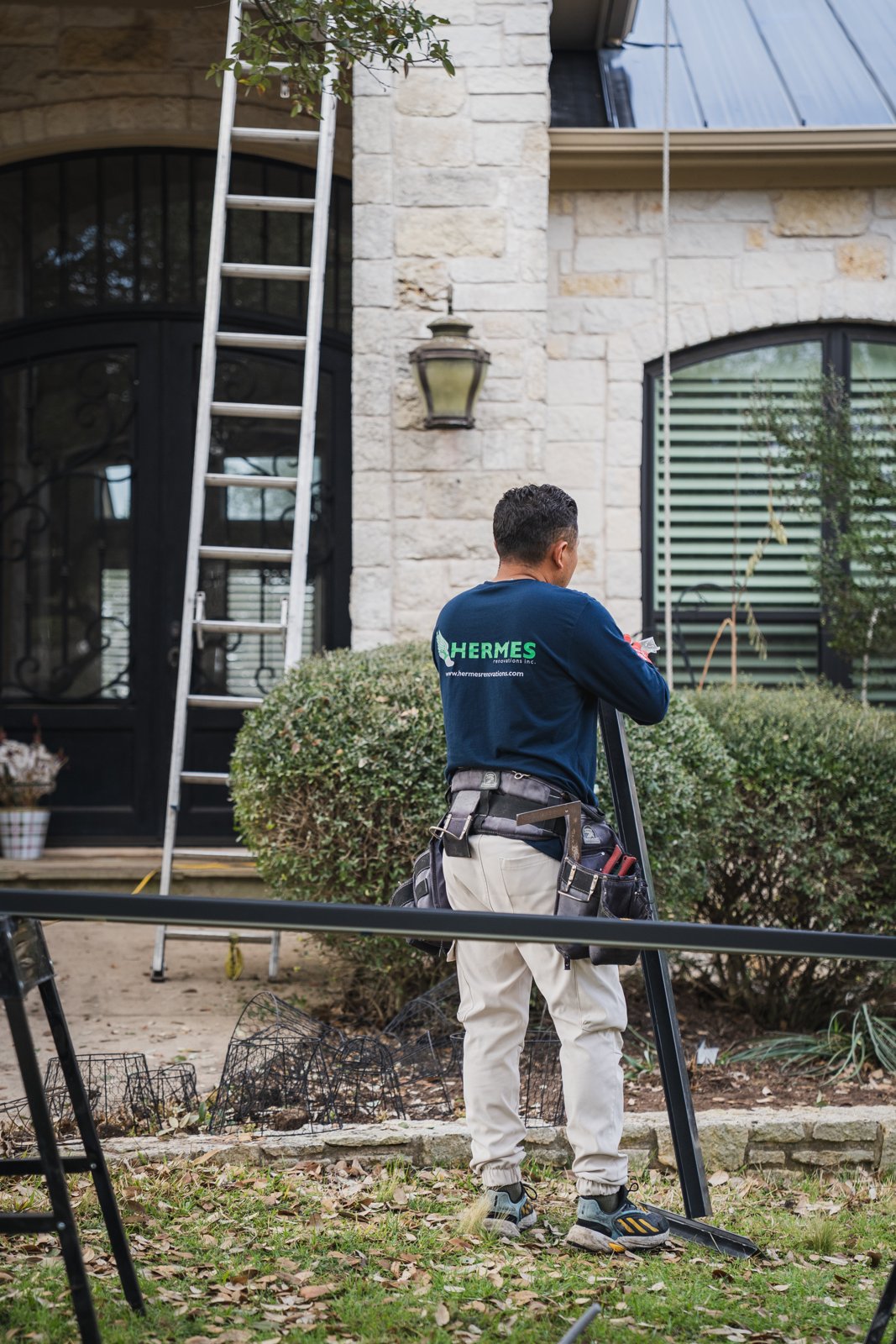 Hermes Roofing crew member in company shirt preparing trim on site