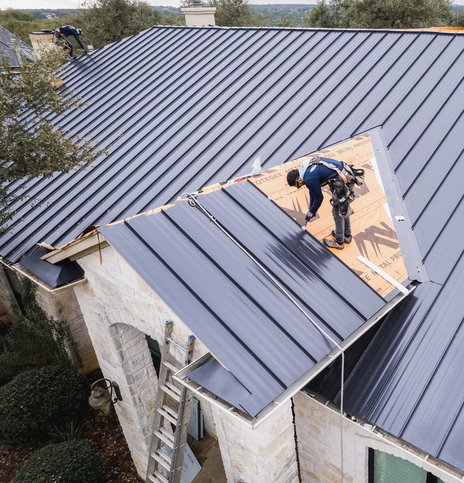Hermes Roofing crew installing a standing seam metal roof in Driftwood, Texas, drone view