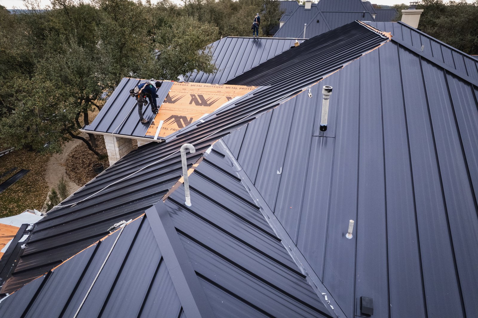 Drone view down the ridge with crew members installing metal panels
