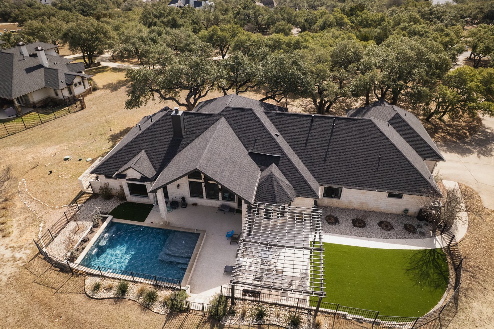 New shingle roof on a limestone home with pool and pergola, aerial view